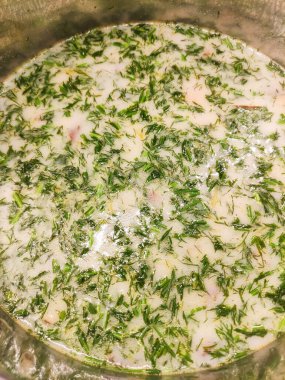 Metal bir tencerede kaynayan kremalı dereotu çorbası, taze dereotu filizleri ve pürüzsüz, kadife gibi bir dokusu olan, rahatlatıcı ve lezzetli bir mutfak deneyimi sunar.