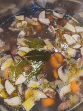 Dilimlenmiş mantarlar ve kokulu kokulu yapraklar pırıl pırıl, paslanmaz çelik bir tencerede kaynayan lezzetli ve aromatik mantar çorbası her yemek için mükemmel olur.