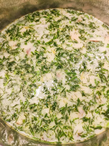 Metal bir tencerede kaynayan kremalı dereotu çorbası, taze dereotu filizleri ve pürüzsüz, kadife gibi bir dokusu olan, rahatlatıcı ve lezzetli bir mutfak deneyimi sunar.