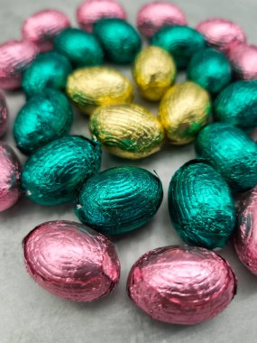 Pink, gold, and teal foil wrapped chocolate easter eggs arranged on a gray surface, evoke the joy and traditions of springtime celebrations in prague, czechia