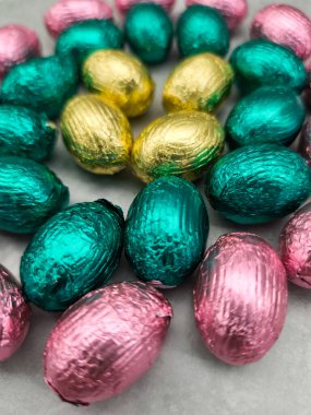 Chocolate eggs wrapped in pink, gold, and teal foil create a festive arrangement celebrating orthodox easter and spring joy