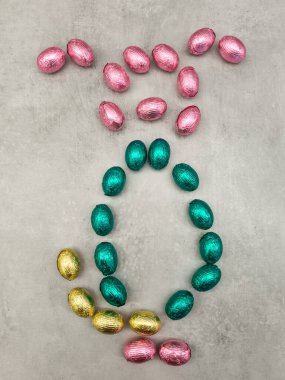 Colorful chocolate easter eggs arranged in the shape of a rabbit on a textured surface, celebrating the joy and traditions of orthodox easter