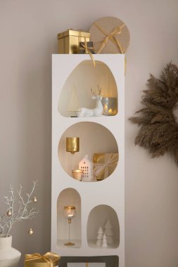 Noel süslemeleri, ışıkları, hediyeleri, fenerleri, geyikleri, mumları, yıldızları ve aksesuarları olan beyaz tasarım rafında güzel bir kompozisyon. Noel Baba geliyor. Şablon. 