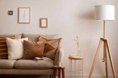 Oturma odasının iç dekorasyonu bej kanepe, yastık, ekose, lamba, sehpa ve kişisel aksesuarlarla. Bej renkli duvar ve sahte poster. Ev dekoru. Şablon.