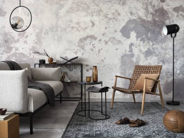 Tasarım gri kanepe, sandalye, yuvarlak lamba, siyah sehpa, dekorasyon, yastık ve zarif aksesuarlarla oturma odasının zarif ve modern kompozisyonu. Beton grunge duvar. 