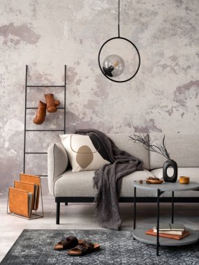 Tasarım gri kanepe, sandalye, yuvarlak lamba, siyah sehpa, dekorasyon, yastık ve zarif aksesuarlarla oturma odasının zarif ve modern kompozisyonu. Beton grunge duvar.