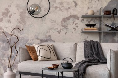 Ekose, sehpa ve kişisel aksesuarları olan gri kanepeli modern oturma odasının Indiustral tarzı. Gri beton duvar. Ev dekoru. Şablon.