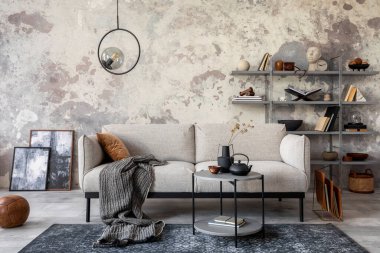 Gri kanepe, ekose, halı, kahve sehpası lambası, kitap rafı ve zarif kişisel aksesuarları olan modern bir daire. Gri beton duvar. Yaratıcı ev dekorasyonu. Şablon