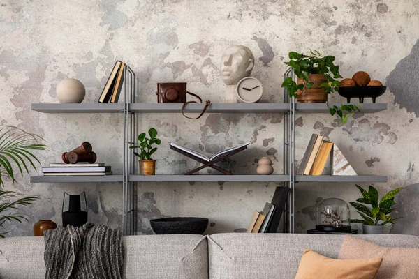 Loft style of modern living room with rack, books, plants, grey sofa and personal accessories. Gray grunge concrete wall. Home decor. Template.