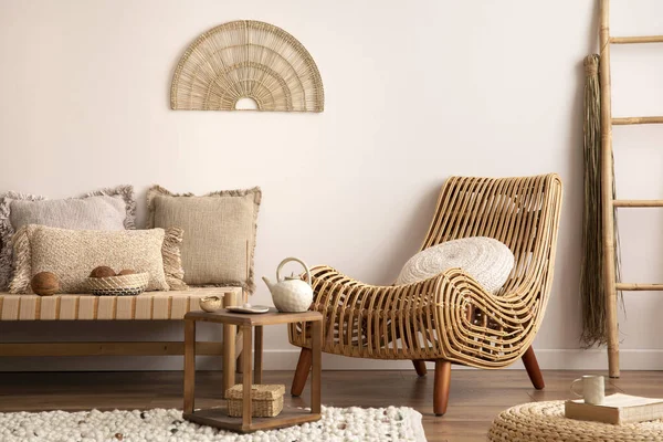 Sunny and bright composition of meditation living room interior with armchair, beige carpet, pillows, ornament and personal accessories. Home decor. Template.