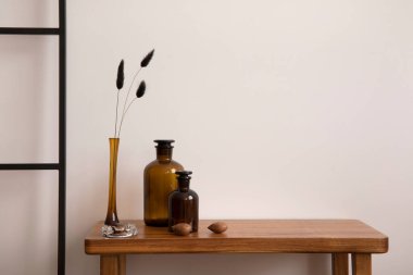 Oturma odasının içi eski ve rahat, içinde fotokopi alanı, bej duvar, kurumuş çiçekli cam vazo, ahşap konsol ve kahverengi aksesuarlar var. Ev dekoru. Şablon. 