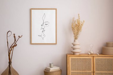 Oturma odasının minimalist kompozisyonu poster çerçevesi, kurutulmuş çiçekli bej vazo, ahşap yuvarlak sehpa, rattan klozet, dekorasyon ve kişisel aksesuarlar. Şık bir ev dekoru. Şablon. 