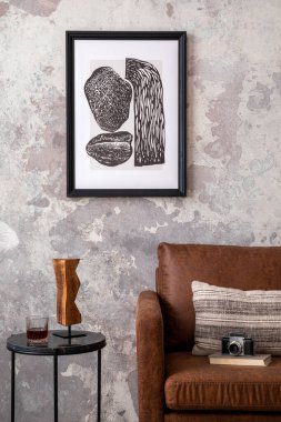 Çatı katı tarzı, poster çerçevesi, yuvarlak sehpa, kahverengi kanepe, yastık, bej kitap, ahşap heykel, kamera ve kişisel aksesuarlar. Ev dekoru. Şablon. 