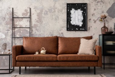 Poster çerçevesi, kahverengi kanepe, merdiven, sehpa, siyah klozet ve kişisel aksesuarları olan bir çatı katı tasarımı. Beton gri duvar. Posteri düzenle. Ev dekoru. Şablon. 