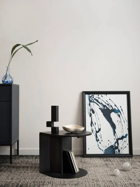 Minimalist composition of elegant and outstanding space with mock up poster frame, dark coffee table, decoration, book, stylish personal accessories and leaf in vase. Minimalist home decor. Template.