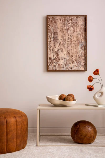 Elegant composition of living room interior with mock up poster frame, brown pouf, stylish bowl with coconut, vase with dried flowers, decoration, coffee table and personal accessories. Home decor. Template.