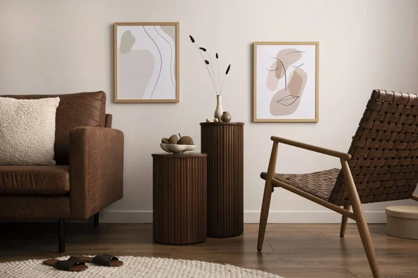 Minimalist composition of elegant and warm space with brown sofa, wooden side tables, rattan armchair, mock up poster frames, round rug, decoration and elegant personal accessories. Home decor.