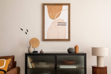 Creative composition of living room interior with mock up poster frame, black commode, lamp on the wooden stand, vase with dried flowers, candle and elegant personal accessories. Home decor. Template.