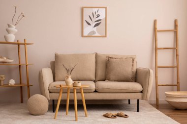 Creative composition of living room interior with mock up poster frame, elegant beige sofa, wooden round coffee table, mirror, bright rug, ladder, white vase with dried flowers and personal accessories. Home decor. Template.