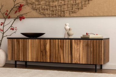 Minimalist composition of japandi living room interior with modern paint, wooden sideboard, vase with red rowan, carpet, bowl, candlestick, books and personal accessories. Home decor. Template.