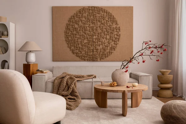Creative composition of living room interior with mock up poster frame, beige sofa, wooden coffee table, rounded shapes armchair, vase with rowanberry and personal accessories. Home decor. Template