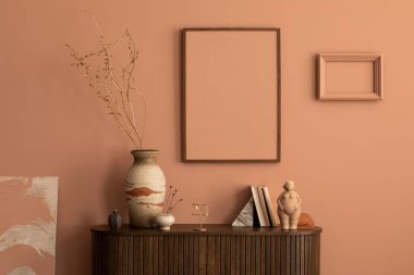 Aesthetic interior of living room with mock up poster frame, wooden commode, vase with dried flowers, sculpture in the shape of a woman, pink wall, books and personal accessories. Home decor. Template