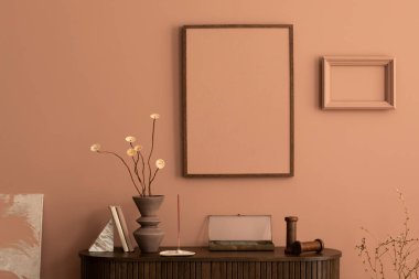 Aesthetic interior of living room with mock up poster frame, wooden commode, vase with dried flowers, sculpture in the shape of a woman, pink wall, books and personal accessories. Home decor. Template. 