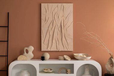 Minimalist composition of living room interior with mock up poster frame, white commode, ladder, vase with dried flowers, modern sculpture, casket, bowl and personal accessories. Home decor. Template.