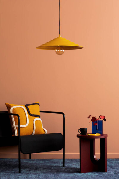 Warm and cozy living room interior with black armchair, round coffee table, patterned pillow, navy carpet, vase with dried flowers and personal accessories. Home decor. Template. 