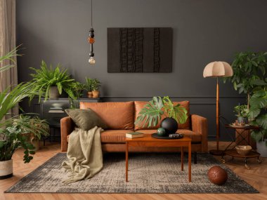 Interior design of living room interior with mock up poster frame, brown sofa, plants, wooden coffee table, lamp, ball, stylish rug, plaid, pillows and personal accessories. Home decor. Template. 