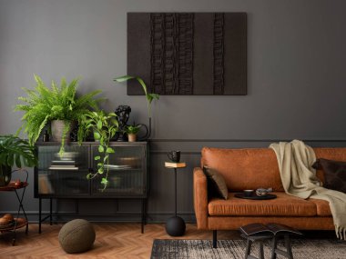 Cozy composition of living room interior with mock up poster frame, brown sofa, plants,  glass sideboard, stool, wooden floor, lamp and personal accessories. Home decor. Template. 