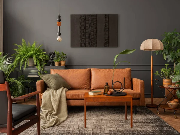 Creative composition of living room interior with mock up poster frame, brown sofa, plants, wooden coffee table, lamp, ball, stylish rug, plaid, pillows and personal accessories. Home decor. Template.