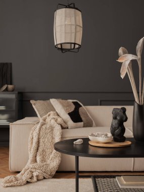 Interior design of elegant living room with modular sofa, patterned pillows, plaid, vase with dried flowers, lamp, sculpture, bowl, books, dark wall and personal accessories. Home decor. Template.