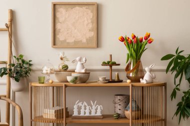 Interior design of easter living room interior with mock up poster frame, glass vase with tulips, wooden sideboard, easter bunny sculpture, bowl, ladder, and personal accessories. Home decor. Template