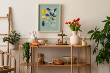 Warm and cozy composition of easter  living room interior with mock up poster frame, vase with tulips, hare sculpture, carrot, bowl, wooden sideboard and personal accessories. Home decor. Template. 