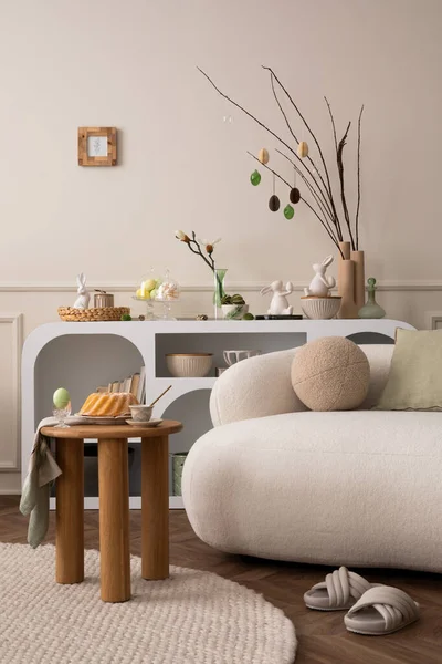 Spring composition of easter living room interior with mock up poster frame,  modern sideboard, coffee table easter cake, eggs, round pillow, easter bunny and personal accessories. Home decor Template