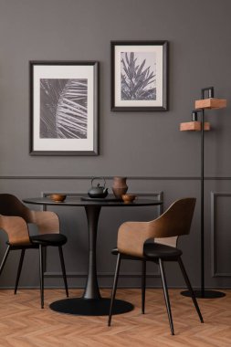 Elegant composition of living room interior with mock up poster frame, black round table, stylish chair, wooden floor, lamp, wall with stucco, pitcher and personal accessories. Home decor. Template.