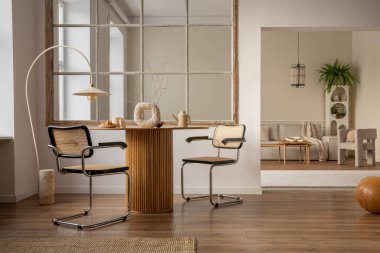 Creative composition of open space interior with round table, rattan chair, vase with dried flowers, window, modular sofa, stylish rack, armchair, lamp and personal accessories. Home decor. Template.