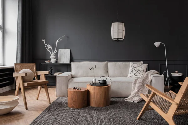 Interior design of living room interior with modular sofa, wooden coffee table, dark wall, rattan armchair, grey rug, beige bowl, patterned pillow, lamp and personal accessories. Home decor. Template.
