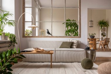 Interior design of open space interior with modular sofa, big window, stylish lamp, wooden coffee table, round table, rattan chair, pillows, plants and personal accessories. Home decor. Template.