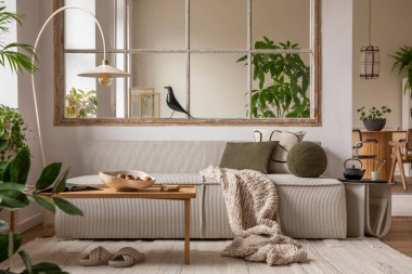 Open space interior with modular sofa, wooden coffee table, big window, patterned pillows, braided plaid, stylish lamp, wooden coffee table, plants and personal accessories. Home decor. Template.