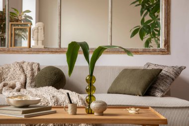 Aesthetics composition of open space interior with modular sofa, wooden coffee table, cup window, braided plaid, books, bowl, glass vase with leaves and personal accessories. Home decor. Template. 
