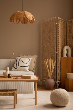 Modüler kanepe, bölme duvarı, ahşap sehpa, yuvarlak yastık, kurumuş çiçekli vazo, rattan lambası ve kişisel aksesuarları olan bir oturma odasının estetik bileşimi. Ev dekoru. Şablon