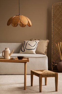 Modüler kanepe, bölme duvarı, ahşap sehpa, yuvarlak yastık, kurumuş çiçekli vazo, rattan lambası ve kişisel aksesuarları olan bir oturma odasının estetik bileşimi. Ev dekoru. Şablon