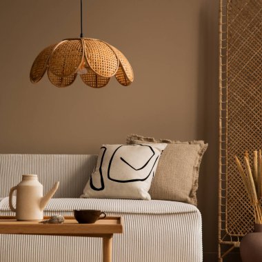 Modüler kanepe, bölme duvarı, ahşap sehpa, yuvarlak yastık, kurumuş çiçekli vazo, rattan lambası ve kişisel aksesuarları olan bir oturma odasının estetik bileşimi. Ev dekoru. Şablon