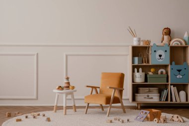 Fotokopi alanı, turuncu koltuk, ahşap büfe, yuvarlak tabure, bej halı pelüşlü oyuncaklar, ahşap bloklayıcılar ve kişisel aksesuarlarla çocuk odasının minimalist kompozisyonu. Ev dekoru. Şablon.
