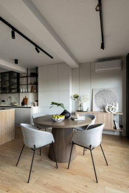 Modern yemek odasının iç tasarımı yuvarlak masa, gri sandalye, armut ve ahşap zemin. Gri daire. Ev dekoru. Şablon.