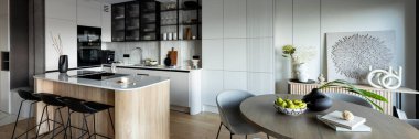 Mutfak odasının modern kompozisyonu mutfak adası, siyah fahişeler, gri masa, çiçekler, mobilyalar, büyük pencere ve zarif kişisel aksesuarlar. Şık bir ev dekoru. Şablon