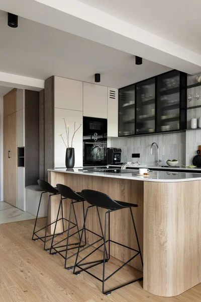 Modern composition of kitchen space with design kitchen island, black hookers, grey table, flowers, furnitures, and elegant personal accessories. Stylish home decor. Template.