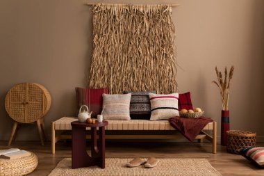 Etno oturma odasının iç tasarımı renkli yastıklar, rattan büfesi, bordo kahve masası, kurutulmuş çiçekli vazo, terlikler ve kişisel aksesuarlarla. Ev dekoru. Şablon. 